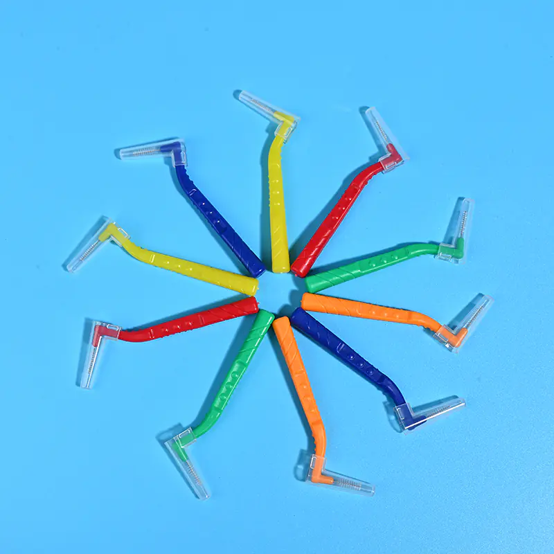 Multicolor rainbow L-type interdental cleaners arranged radial star shape on solid light blue background, color coded for different ISO sizes