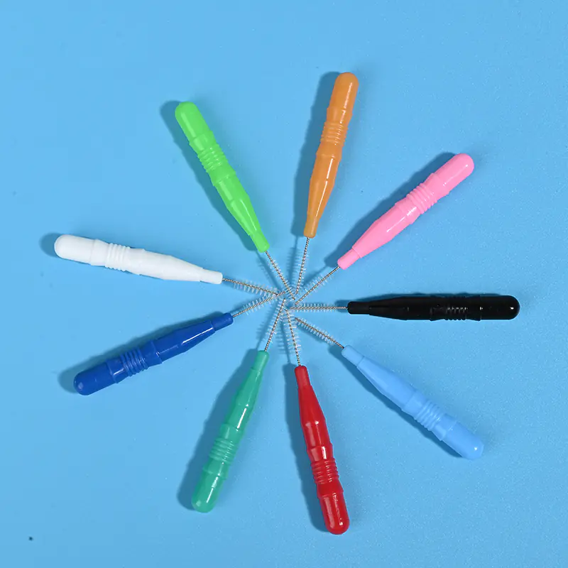 Assorted colored interdental brushes without protective caps arranged radially on light blue background