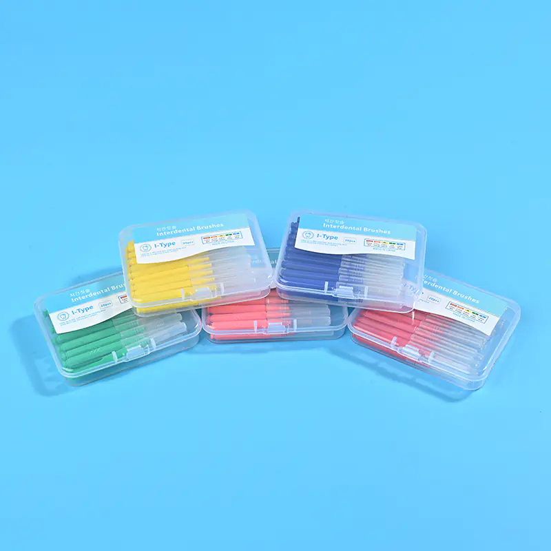 Five different color clear plastic boxes of I-type interdental brushes stacked together on solid light blue background